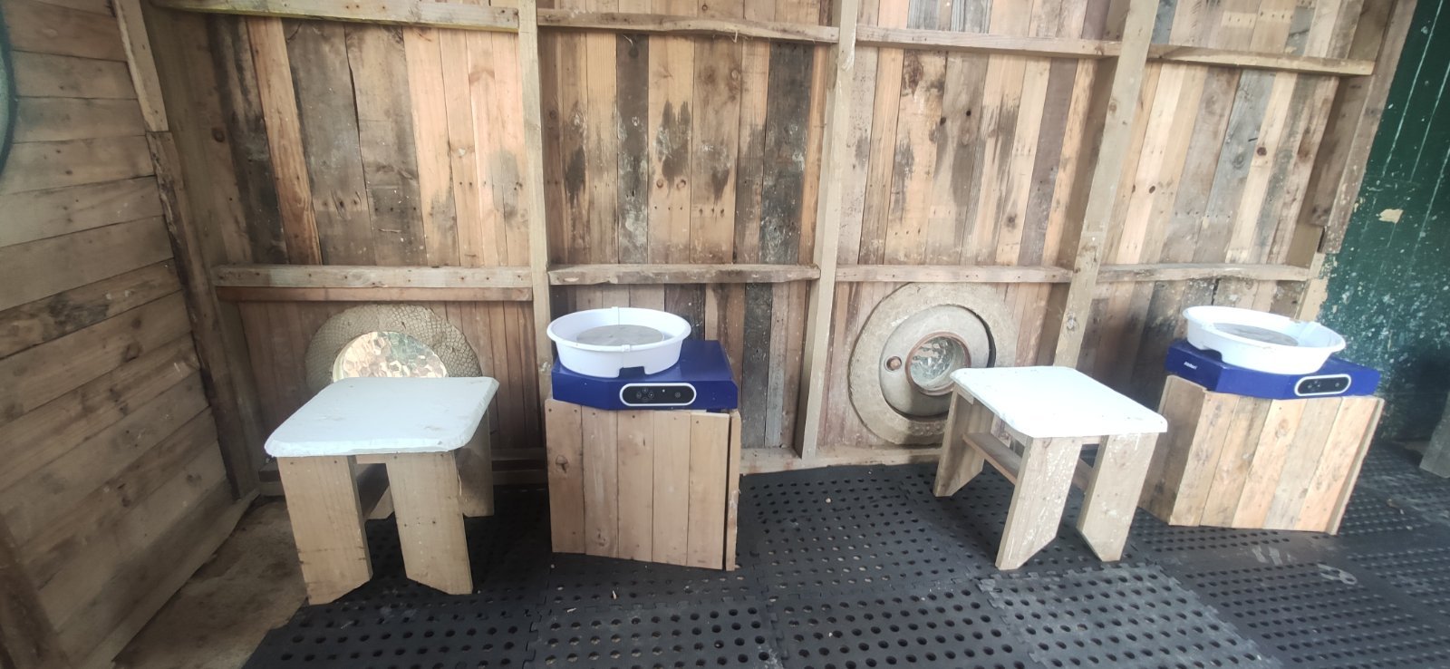 A wide view of the pottery wheel stations inside the rustic Slo Mo Pots studio, set up for an intimate class of two or three students.